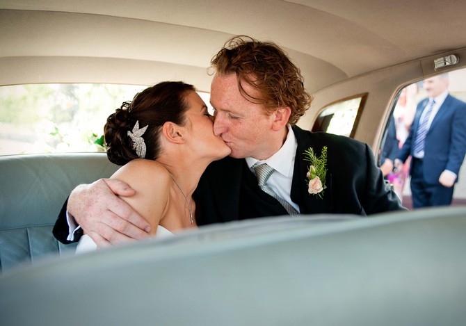 bride and groom kiss in car